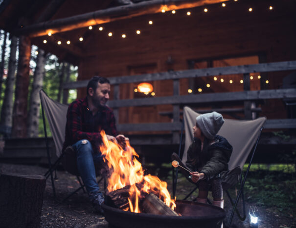 Father and daughter having fun by the campfire at their cabin in the woods