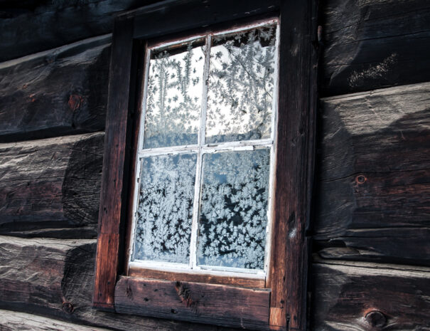 An old house in the winter with snowcrystals on the window.